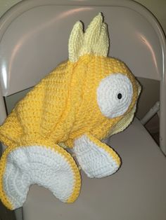 a crocheted stuffed fish sitting on top of a white plastic chair with it's eyes closed