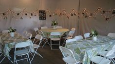 tables and chairs are set up in a tent with lights strung from the ceiling above them