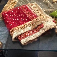 a red and gold purse sitting on top of a glass table next to other items