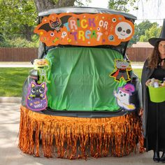 a woman in a witches costume standing next to a trunk with halloween decorations on it