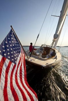 a boat with an american flag on it in the water next to another sailboat