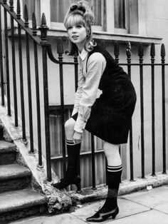 a woman standing on the steps in front of a building wearing knee high socks and boots