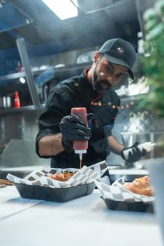 a man in black jacket and gloves preparing food