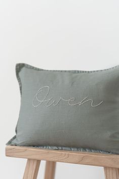 a grey pillow with the word queen embroidered on it