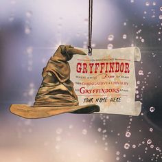 an ornament hanging from a glass window with water droplets on it and the words gryffinndor written in red