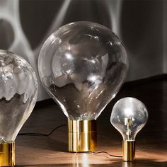 three glass lamps sitting on top of a wooden table