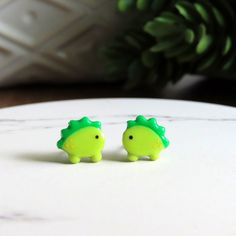 Roar!  DAINTY green dino earrings, on titanium posts, excellent for sensitive ears.  Measures approx 9mm wide.   // DETAILS: * Titanium Post - US Medical Grade * 100% Nickel-free * Hypoallergenic * Fade resistant * Ultra lightweight, durable plastic * High-gloss protective finish * Silicone backs * Handmade in sunny Southeast // SHIPPING: Your order ships FAST within 1-2 business days! Spend $35 or more and you'll receive FREE shipping within the US. Discount automatically applies at checkout. // PACKAGING: Your earrings will arrive in our small branded box, ready for gifting! We always include a pair of spare rubber backings with each earring order. // MORE: Want to see more? Don't forget to "like" the shop to keep up on new releases and restocks! Hit the heart button at the top of the pa Dino Earrings, Heart Button, Kawaii Animals, New Releases, Animal Jewelry, Sensitive Ears, Jewelry Earrings Studs, High Gloss, Don't Forget