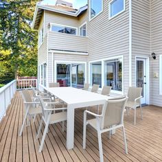 a large white table sitting on top of a wooden deck next to a building with lots of windows