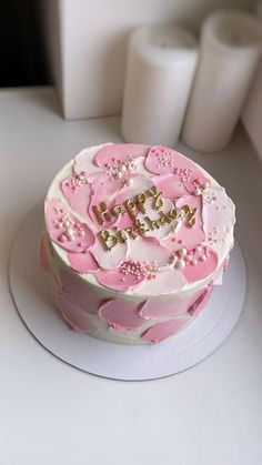 a pink and white birthday cake on a table