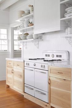 a white stove top oven sitting inside of a kitchen next to wooden cabinets and drawers