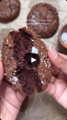 a person holding a chocolate cookie with white sprinkles