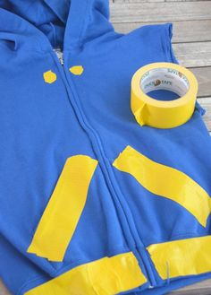 a blue and yellow jacket with tape on top of it next to a wooden bench