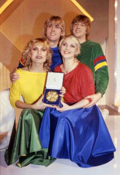 an old photo of some people posing for a picture with one holding a medal and the other standing behind them