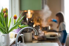 a woman is in the kitchen with her hair dryer and some tulips