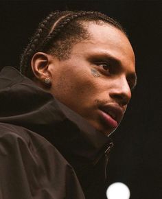 a close up of a person wearing a jacket and piercings on his nose with an apple in the background