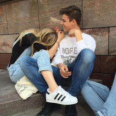 a man and woman sitting on the ground with their hands around each other's heads