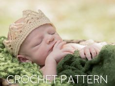 a baby laying on top of a blanket wearing a crochet hat and holding it's hand