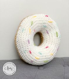 a crocheted donut sitting on top of a gray couch next to a white wall