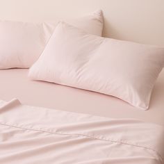 a bed with pink sheets and pillows on it