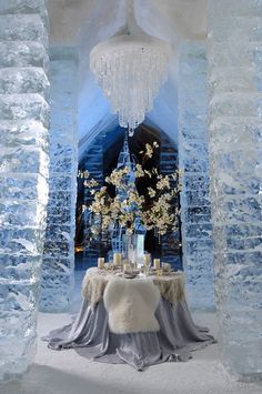 the table is set up in an ice castle like setting with flowers and candles on it