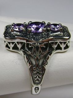 "Purple Amethyst Cubic Zirconia Description 3Stone Rectangle Design#60 MADE TO ORDER This is a lovely Edwardian reproduction 3 gemstone ring in solid sterling silver. The gorgeous filigree ring is set with 3 round cut purple amethyst CZ. The 2 smaller amethyst CZ's are 4.5mm in diameter; and the center amethyst CZ is 6mm in diameter. This filigree setting is a cast from an actual Antique design; notice the amazing etched accents... The ring sits 3/4th\" (19mm) NS on the finger. The quality of th Ornate Silver Amethyst Ring For Anniversary, Vintage Sterling Silver Amethyst Ring With Stone Setting, Silver Sterling Silver Amethyst Ring With Filigree, Silver Amethyst Ring Collectible, Art Deco Amethyst Silver Jewelry, Art Deco Silver Amethyst Jewelry, Silver Amethyst Art Deco Jewelry, Silver Filigree Amethyst Ring, Antique Amethyst Ring With Filigree