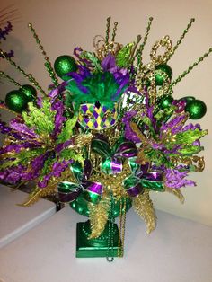 a green vase filled with lots of purple and green decorations on top of a table