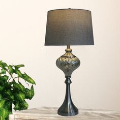 a lamp on a table next to a potted plant