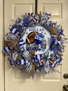 a wreath on the front door decorated with footballs and blue streamers that says, dallas