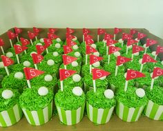 cupcakes with green frosting and golf flags on them are arranged in rows