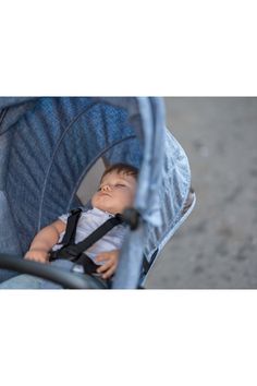 a baby in a blue stroller with his eyes closed