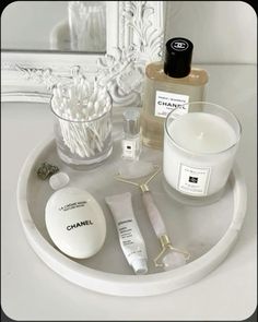 a white tray topped with bottles and candles next to a candle holder filled with personal care items