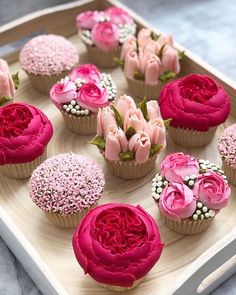 cupcakes decorated with pink and red flowers on a tray