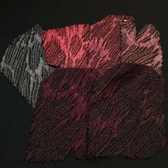 three different colors of fabric sitting on top of a black surface with one red and the other grey