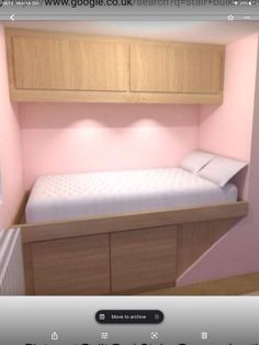 a small bed in the corner of a room with pink walls and wooden cabinets on either side