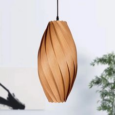 a wooden light hanging from a ceiling in a room with a potted plant behind it