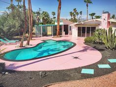 a pool surrounded by palm trees in front of a house