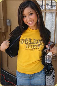 a woman in a yellow shirt is holding her hand on her hip and smiling at the camera