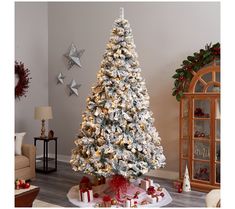 a white christmas tree in a living room decorated with red and gold ornaments, silver star garlands and bows