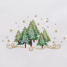 embroidered christmas trees on white fabric with gold stars and snowflakes in the background