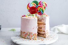 two layered cake with candy and lollipops on top, one slice cut out