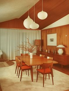 a dining room table with four chairs and a vase on top of it in front of a window