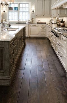 a large kitchen with white cabinets and wood flooring on the walls is pictured in this image