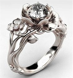 a white gold ring with flowers and leaves on the side, surrounded by a diamond