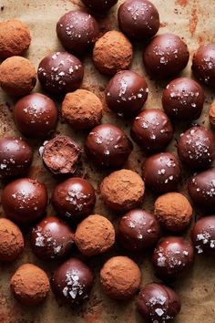 chocolate balls with white sprinkles are on a piece of parchmented paper