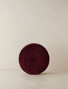 a red round cushion sitting on top of a white table