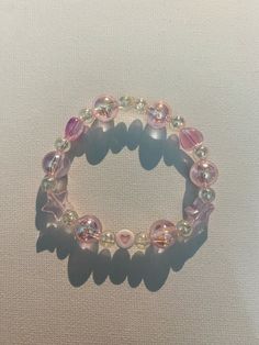 a bracelet with pink beads and hearts on it's end, sitting on a white surface