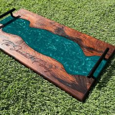 a wooden board with writing on it sitting in the grass next to a pool of water