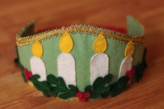 a close up of a green crown on a wooden table with gold trimmings