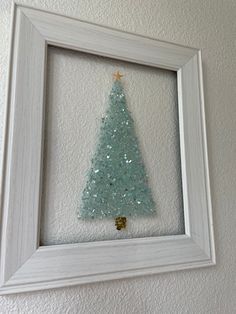 a white frame with a blue christmas tree in it and a gold star on the top