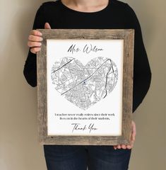 a woman holding up a framed map with the words mr and mrs written on it